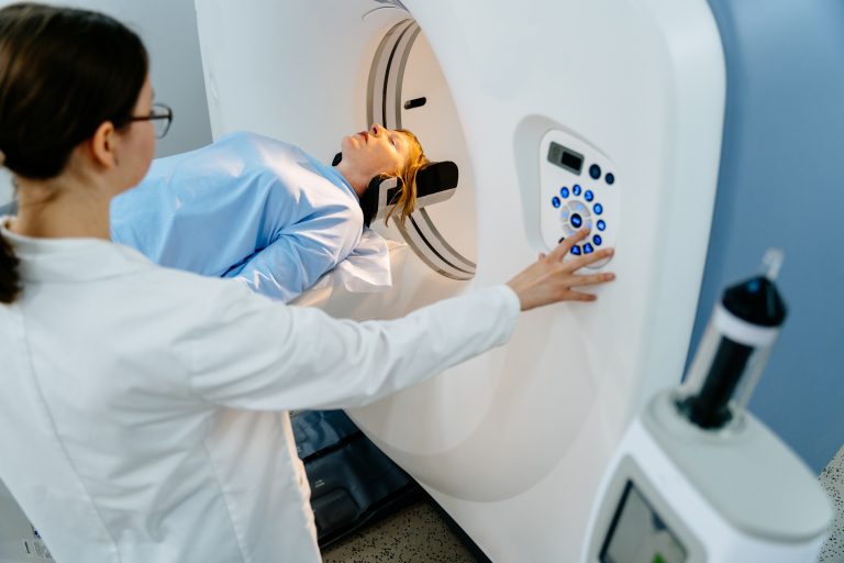 Patient lying in MRI machine, professional oversees operation, ensuring safety and support. Diagnosis and compassionate care in medical treatment processes.
