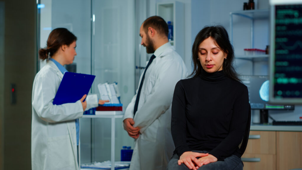 Team of scientists doctor discussing health status of patient, brain functions, nervous system, tomography scan while woman waiting for diagnosis of disease sitting in research laboratory.