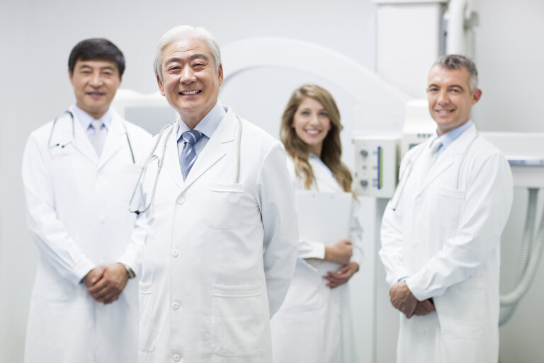 Doctors standing in front of a CT scanner showing that these specialists have the tools to perform proactive heart disease screening.