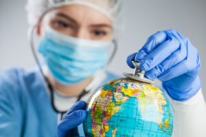 Medical professional examining a globe with a stethoscope, representing medical tourism and international healthcare screening.