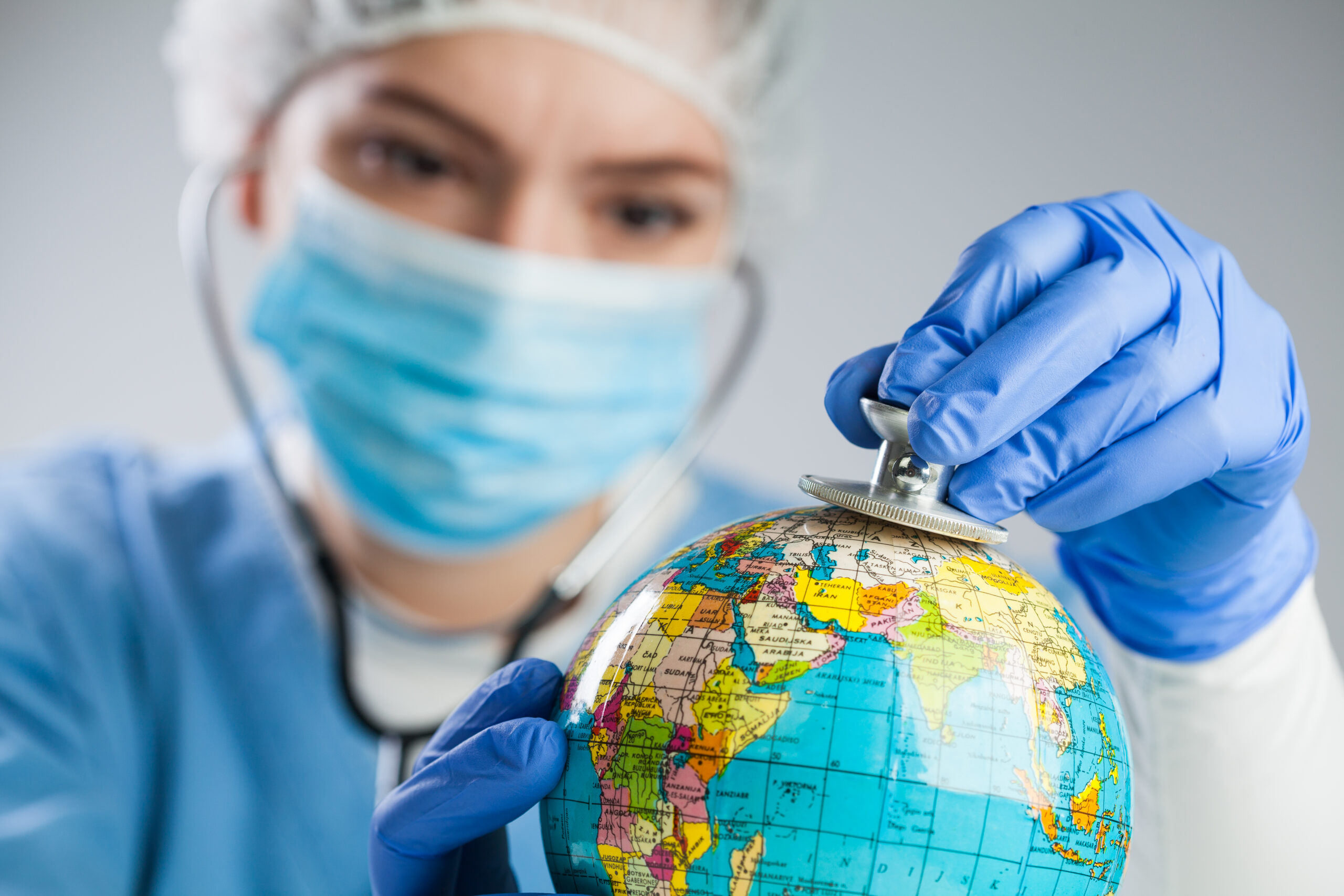 Medical professional examining a globe with a stethoscope, representing medical tourism and international healthcare screening.